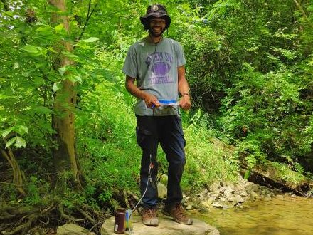 Student intern stands in creek